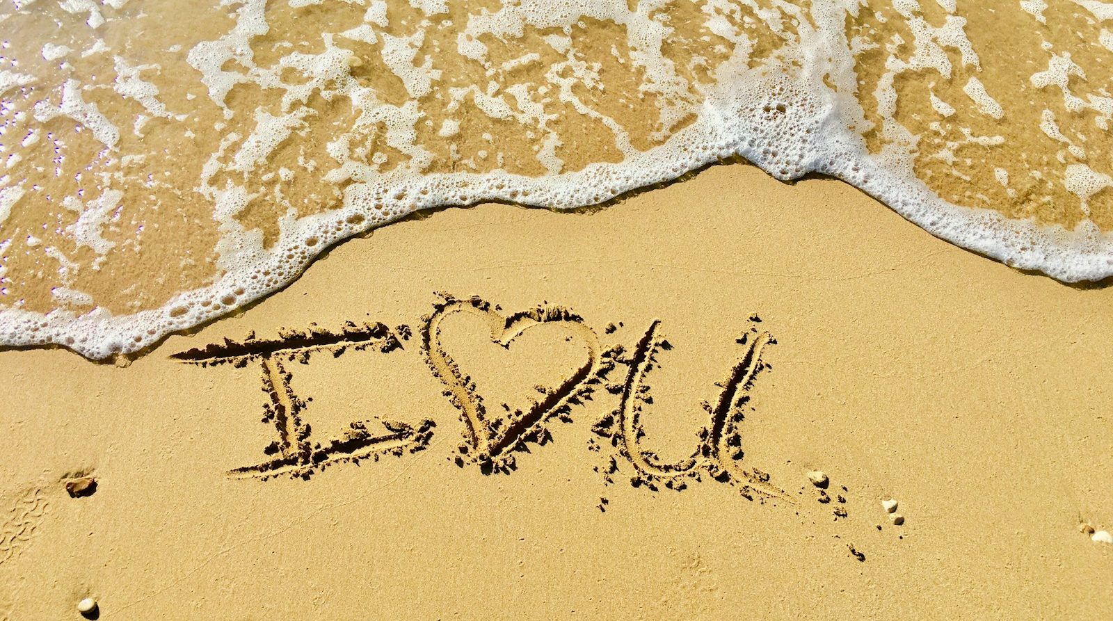 aerial photo of I love you text on sand at the seashore